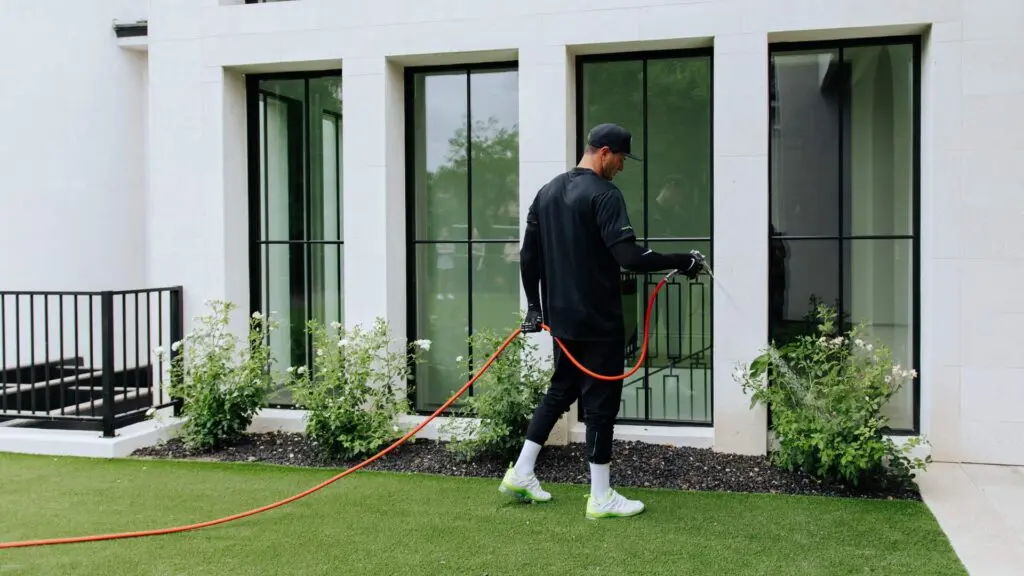 Pest control technician treating the exterior of a home